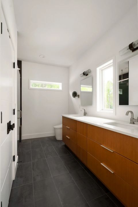 Aiken master bathroom with double vanity, warm wood cabinetry, white quartz countertops, brushed nickel fixtures, and ribbed glass sconces by Tekton Builds.