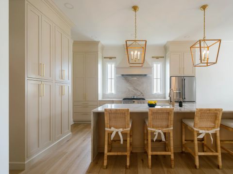 Greenville kitchen renovation with light greige shaker cabinetry, gold hardware, marble island and backsplash, custom range hood, and gold pendant lighting by Tekton Builds.