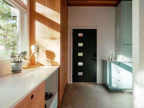 Greenville kitchen with light wood cabinetry, white countertops, black door with glass inserts, pastel blue accent cabinets, and concrete floors by Tekton Builds.